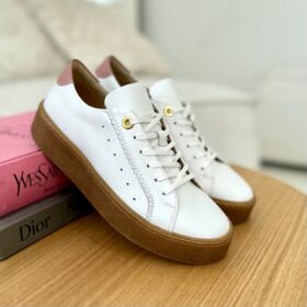 Eleganckie białe sportowe buty Ulmani z beżowym akcentem na pięcie i złotymi oczkami na sznurówki, umieszczone na drewnianym blacie.