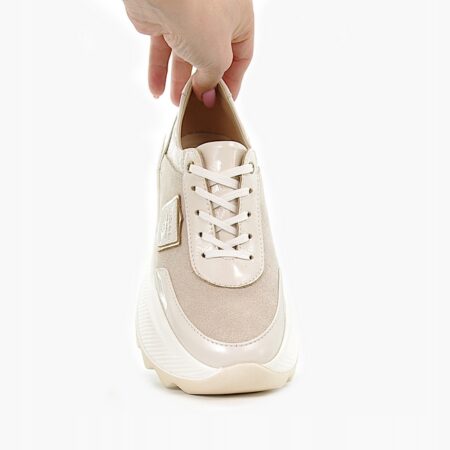 Przedni widok beżowego sneaker'a Ulmani 16533 trzymanego w dłoni, na białym tle, z białymi sznurowadłami i złotą metką.