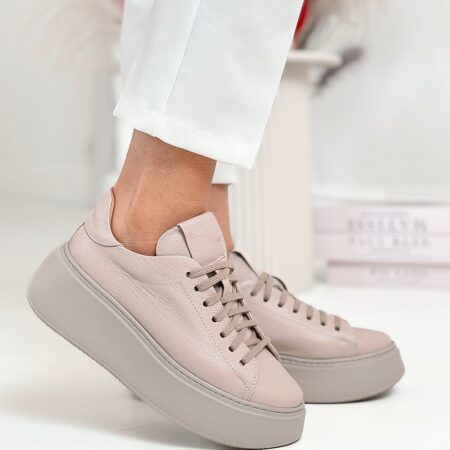 Beżowe sneakersy na wysokiej podeszwie – boczny widok butów w ruchu, modelka lekko unosi nogę.