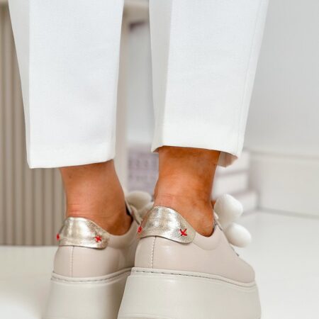 Ujęcie od tyłu przedstawiające pięty w sneakersach chebello, z metalicznym, złotym zapiętkiem i charakterystycznymi czerwonymi przeszyciami w kształcie litery X.