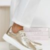 Widok boczny – złote skórzane sneakersy Filippo na modelce, wyraźna faktura skóry i dynamiczna linia podeszwy