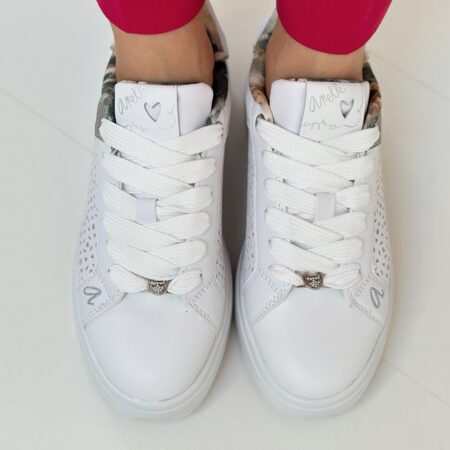 Z góry – białe sneakersy Anekke na stopach, widoczne grube sznurówki i wzór na języku – ażurowe sneakersy